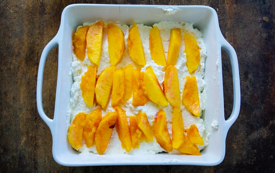 Cream cheese spread on top of graham crackers and topped with peach slices.