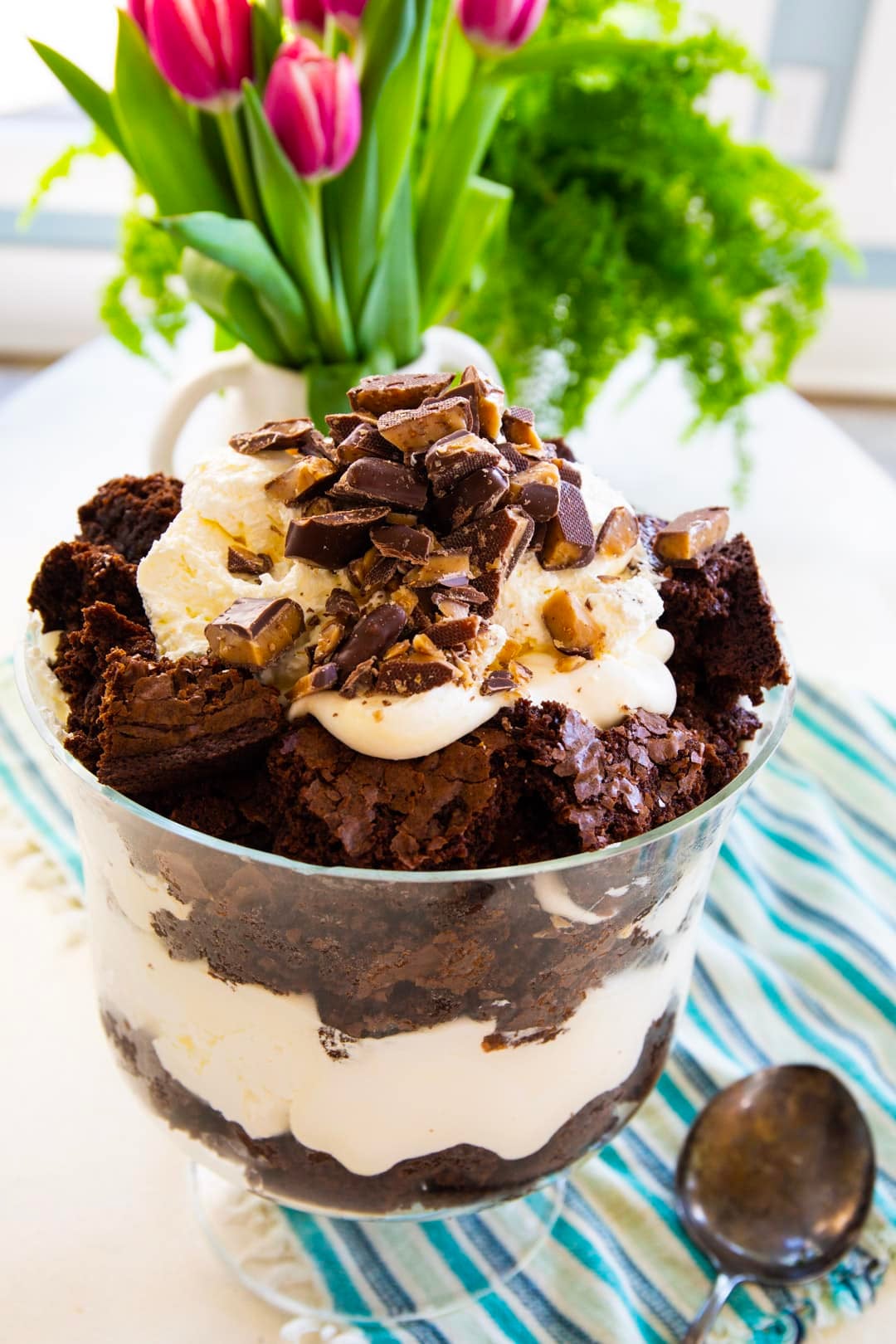 Brownie Trifle in a trifle bowl and tulips in background.