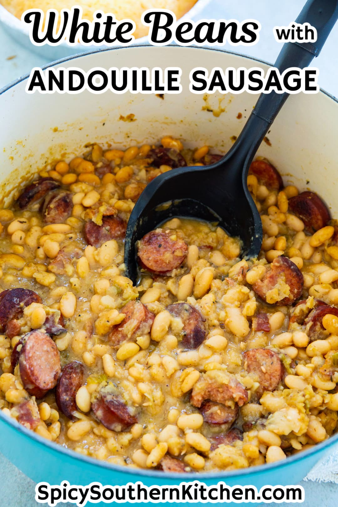 Spoon scooping White beans with sausage out of Dutch oven.