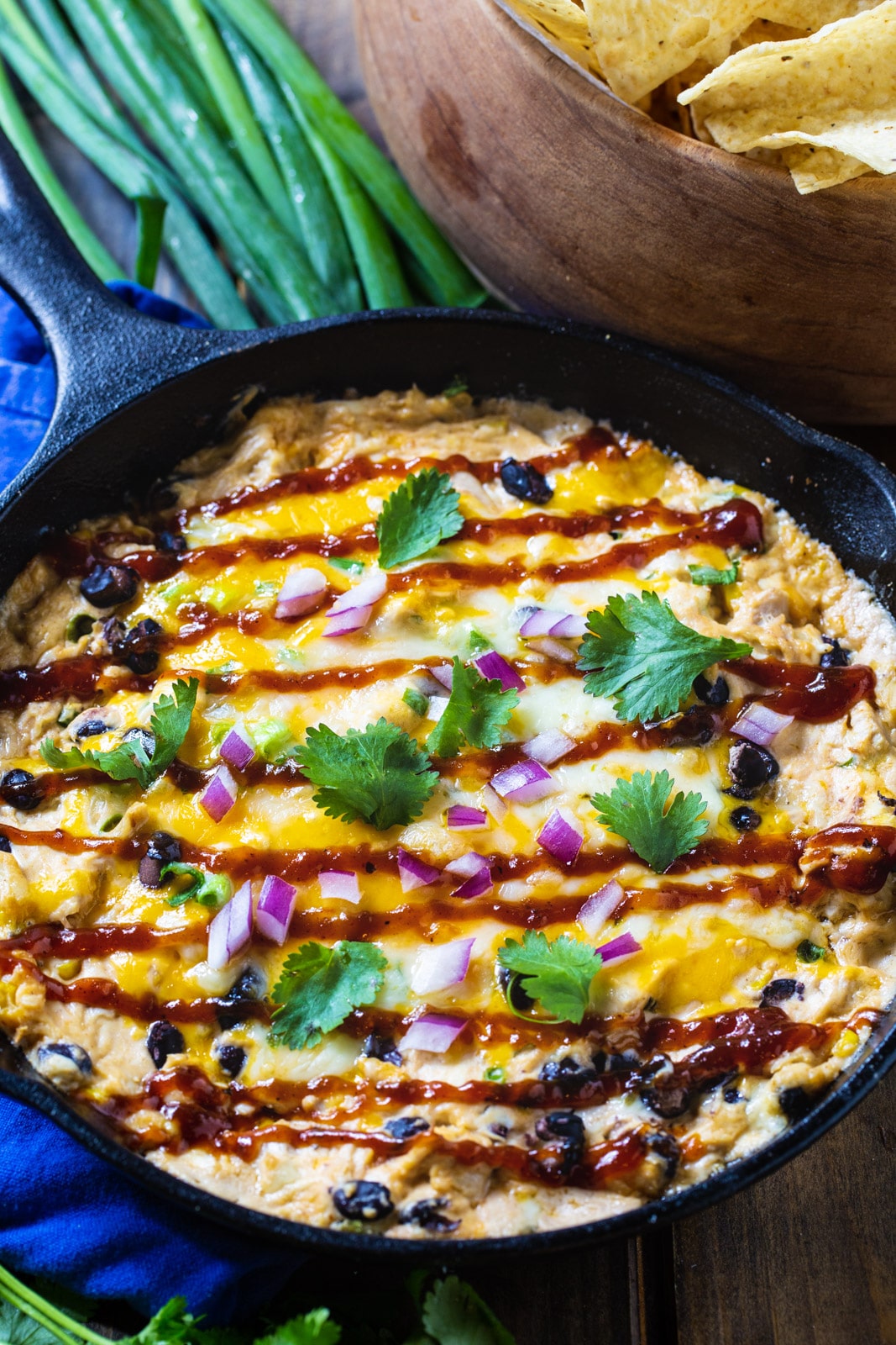 Cooked dip in a skillet with green onions and tortilla chips.