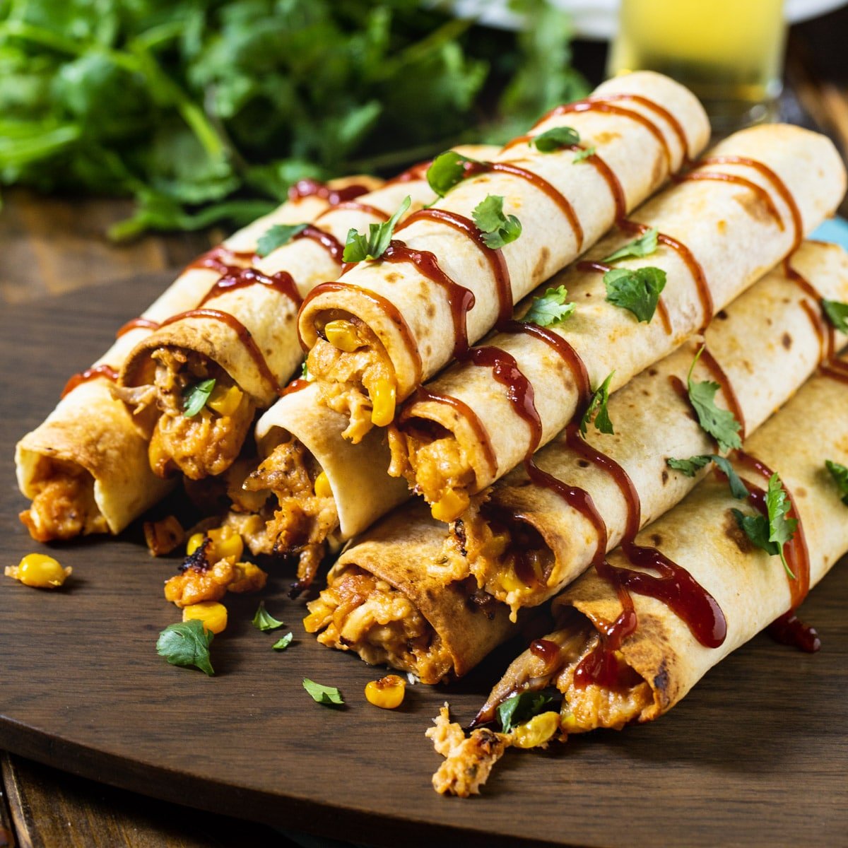 Pile of BBQ Chicken Taquitos on wooden board.
