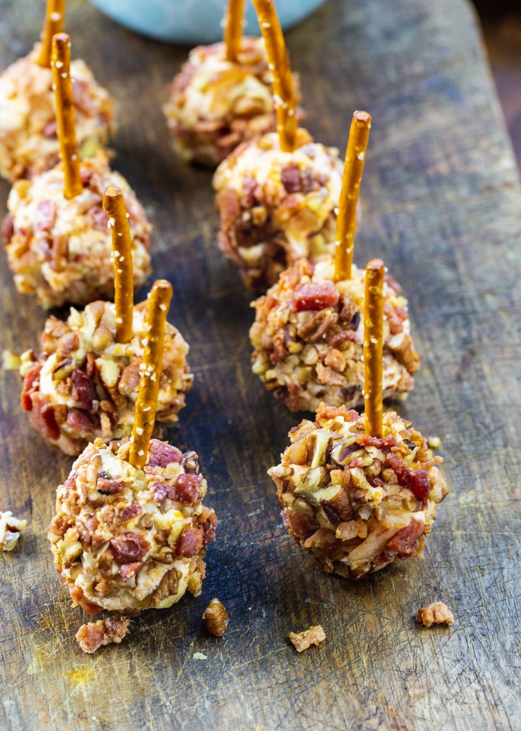 Bacon and Pecan coated Mini Cheese Balls on a wooden cutting board.