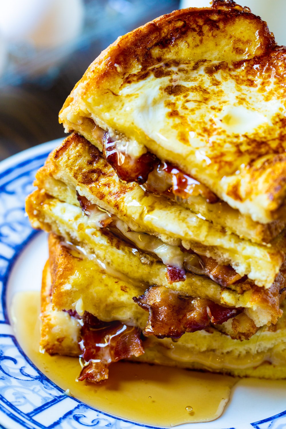 French Toast Stuffed with Bacon piled up with syrup dripping down.