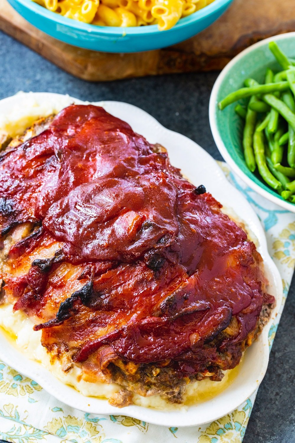 Meatloaf on plate with bowl of green beans.