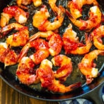 Bacon-Wrapped Shrimp with Pepper Jelly Glaze in a cast iron pan.