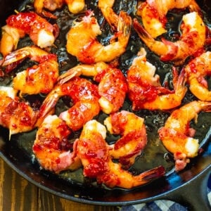 Bacon-Wrapped Shrimp with Pepper Jelly Glaze in a cast iron pan.
