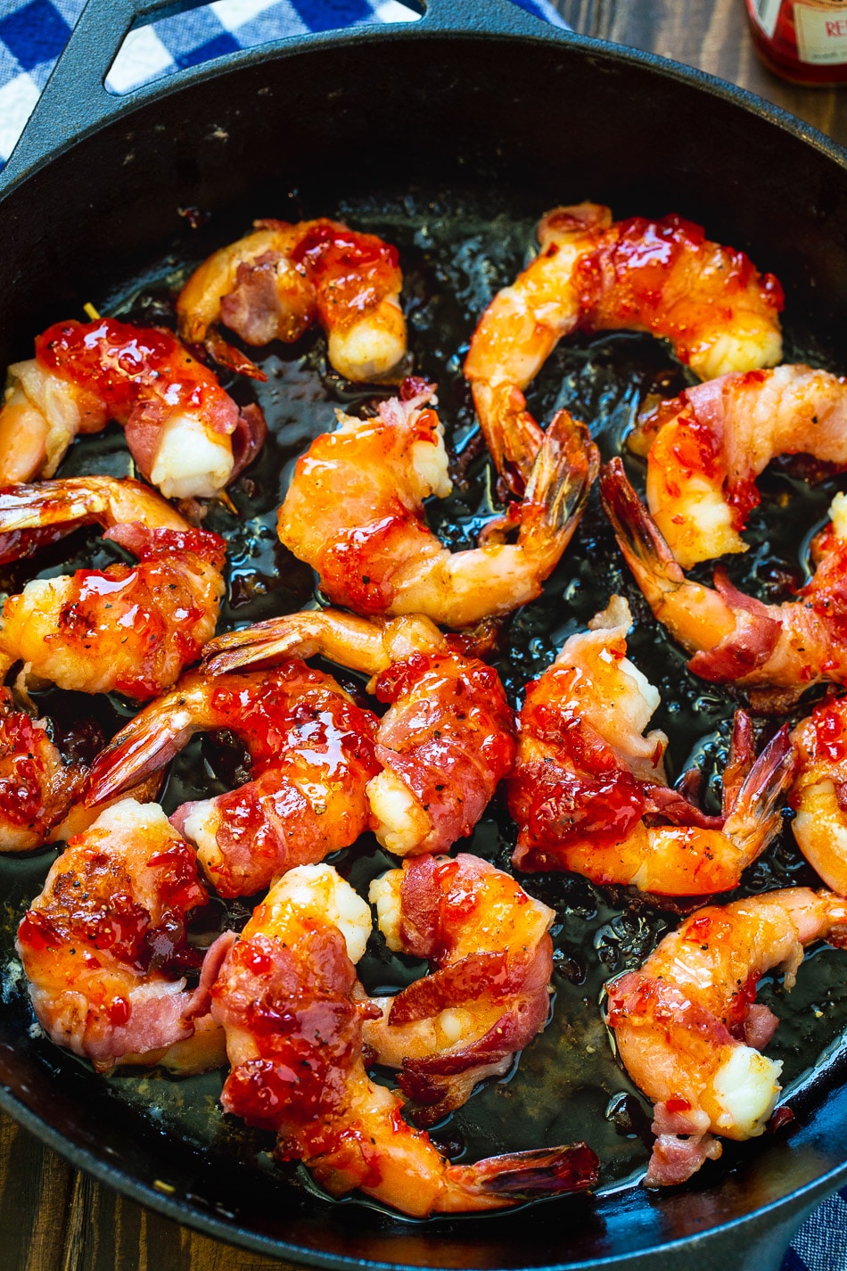 Shrimp wrapped in bacon in cast iron pan.