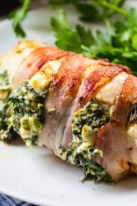 Stuffed Chicken Wrapped In Bacon on a white plate with parsley