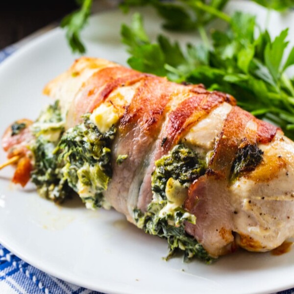 Stuffed Chicken Wrapped In Bacon on a white plate with parsley