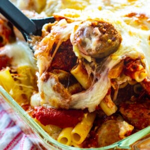 Baked Ziti with Italian Sausage getting scooped out of baking dish.