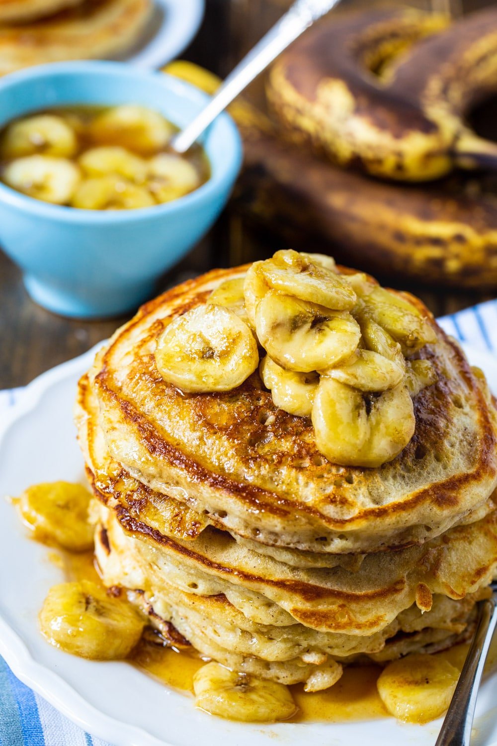 Pancakes stacked on a plate and topped with banana slices.