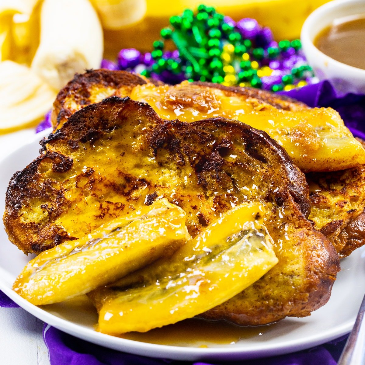 Bananas Foster French Toast on plate with Mardi gras Beads.