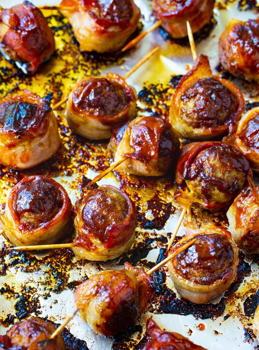 Bacon wrapped meatballs on a baking sheet.