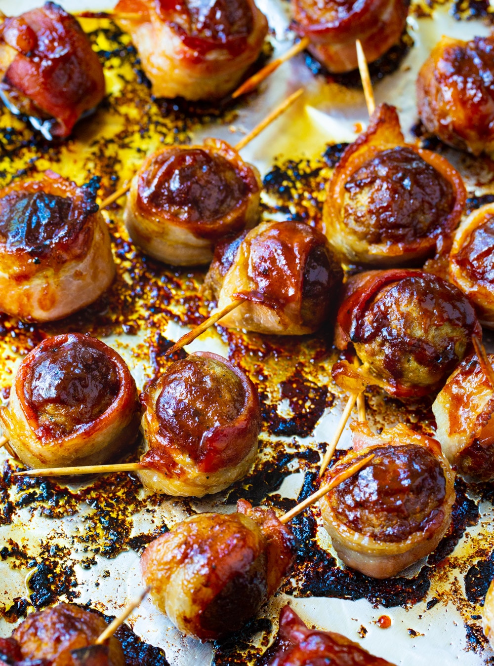 Bacon wrapped meatballs on a baking sheet.