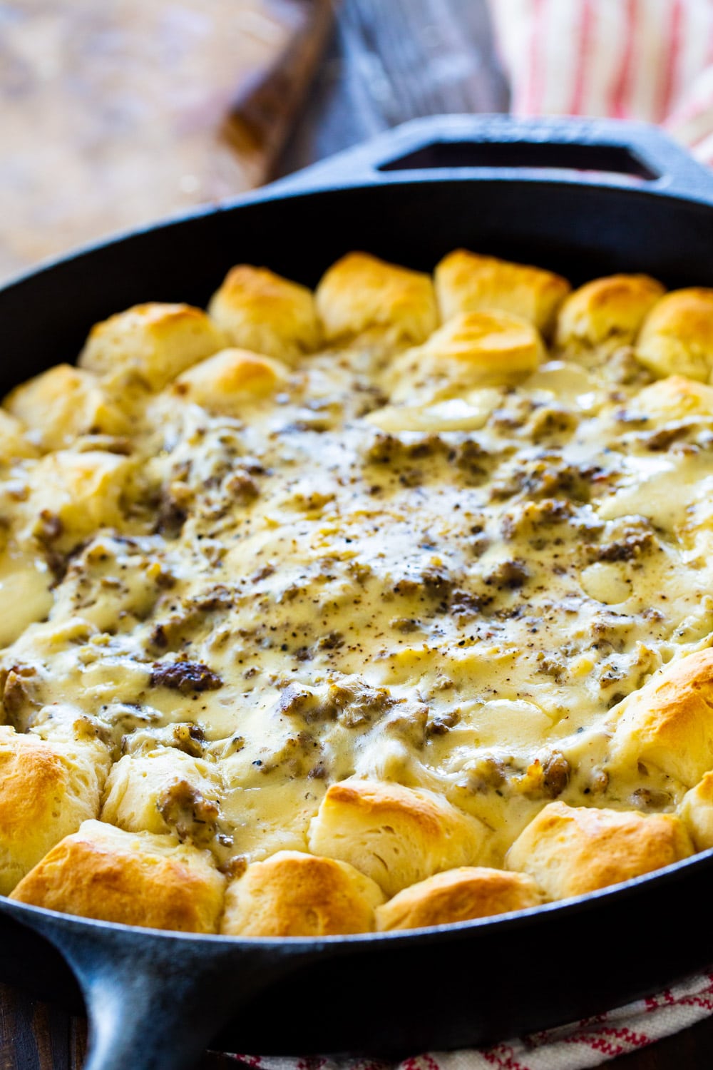 Sausage gravy surrounded by biscuits in a cast iron pan.