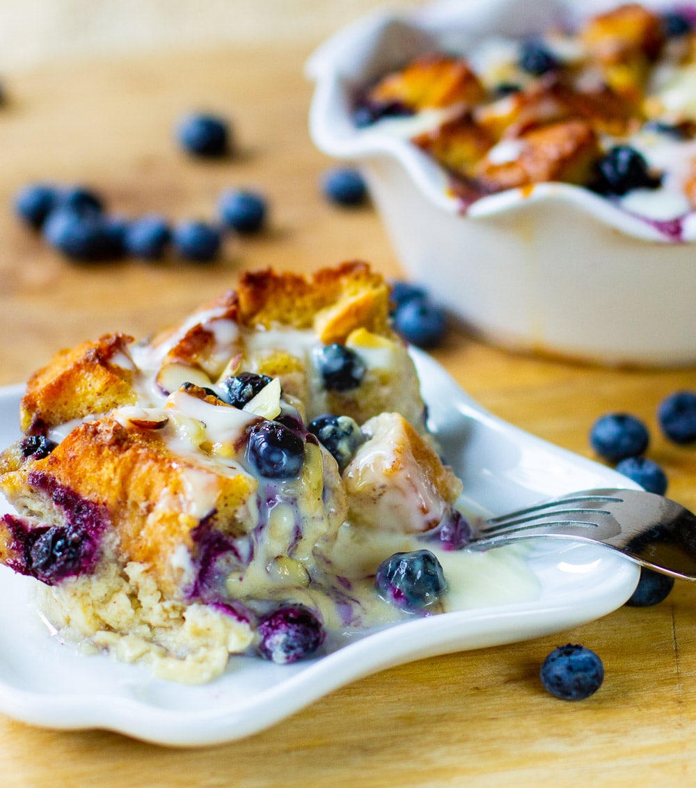 Slice of Bread Pudding with blueberries on a plate.