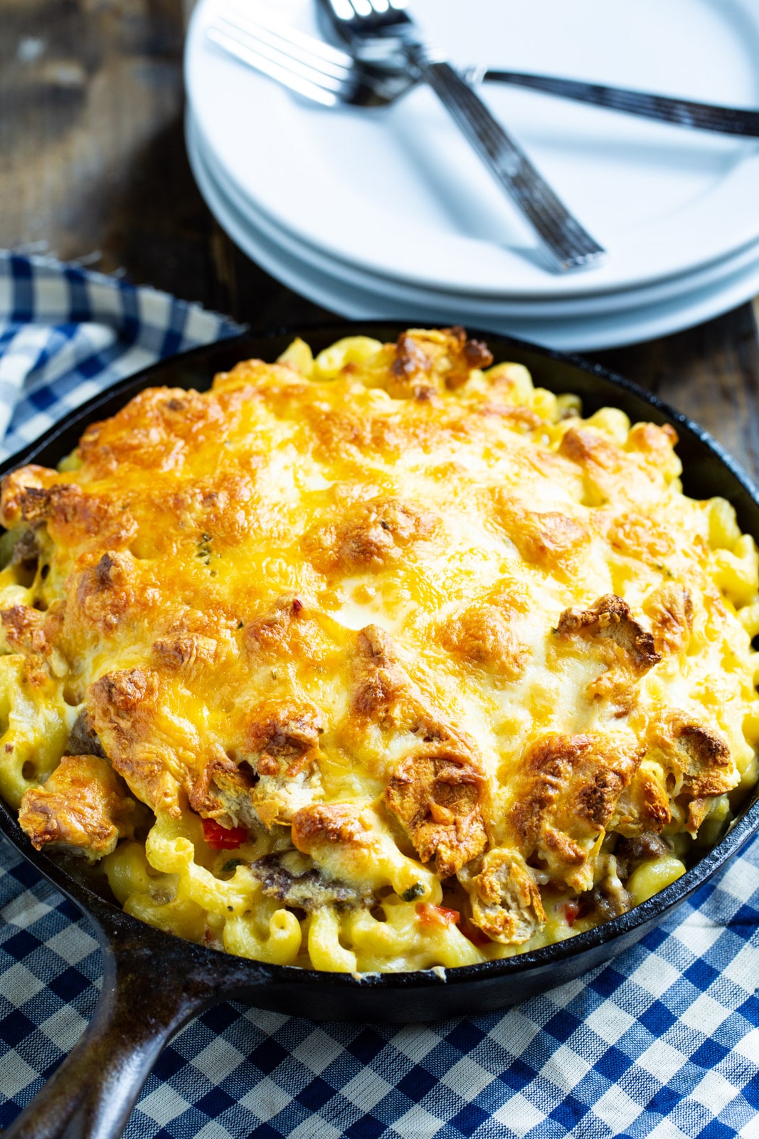 Mac and Cheese in a cast iron pan and a stack of plates.