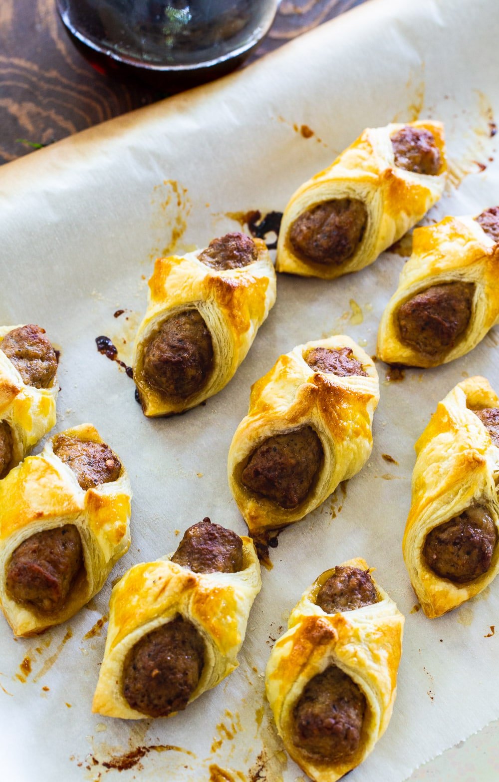 Sausages wrapped in puff pastry on baking sheet.