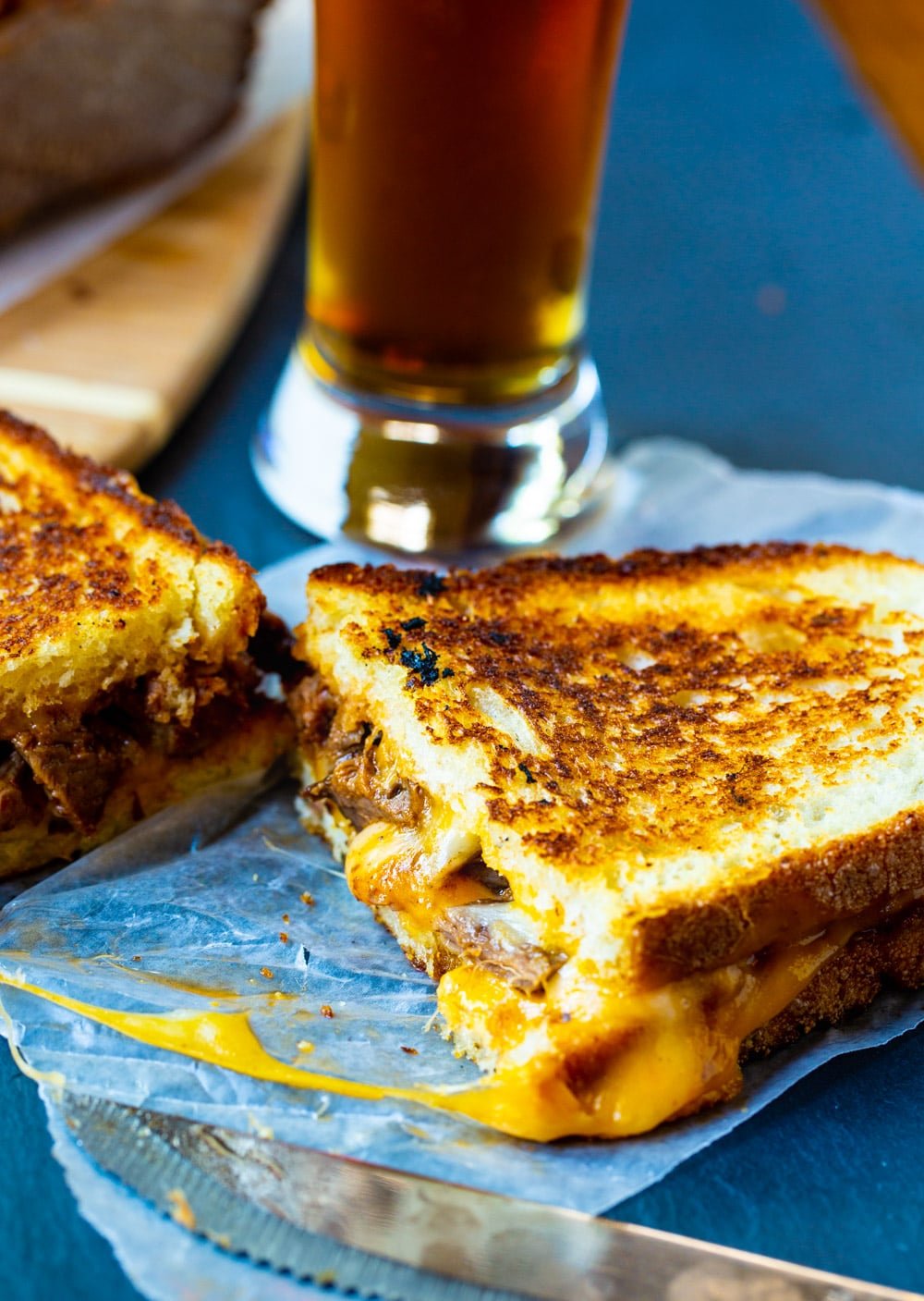 Grilled Cheese cut in half with a glass of beer.