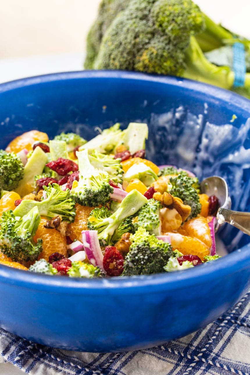 Mandarin Broccoli Salad in a serving bowl with fresh broccoli in background.