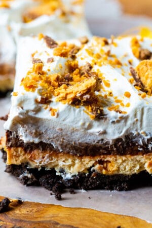 Slice of Butterfinger Chocolate and Peanut Butter Lush on a piece of parchment paper.