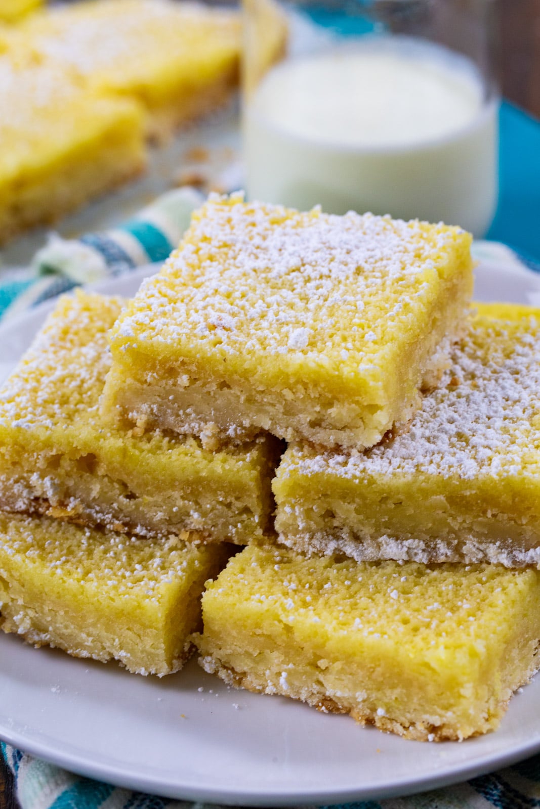 Buttermilk Chess Bars stacked on a plate and a jug of milk.