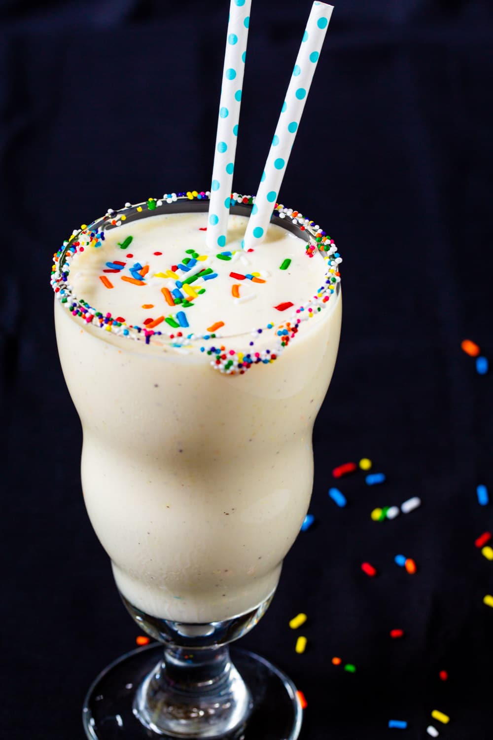 Cake Batter Milkshake in a glass with 2 straws.