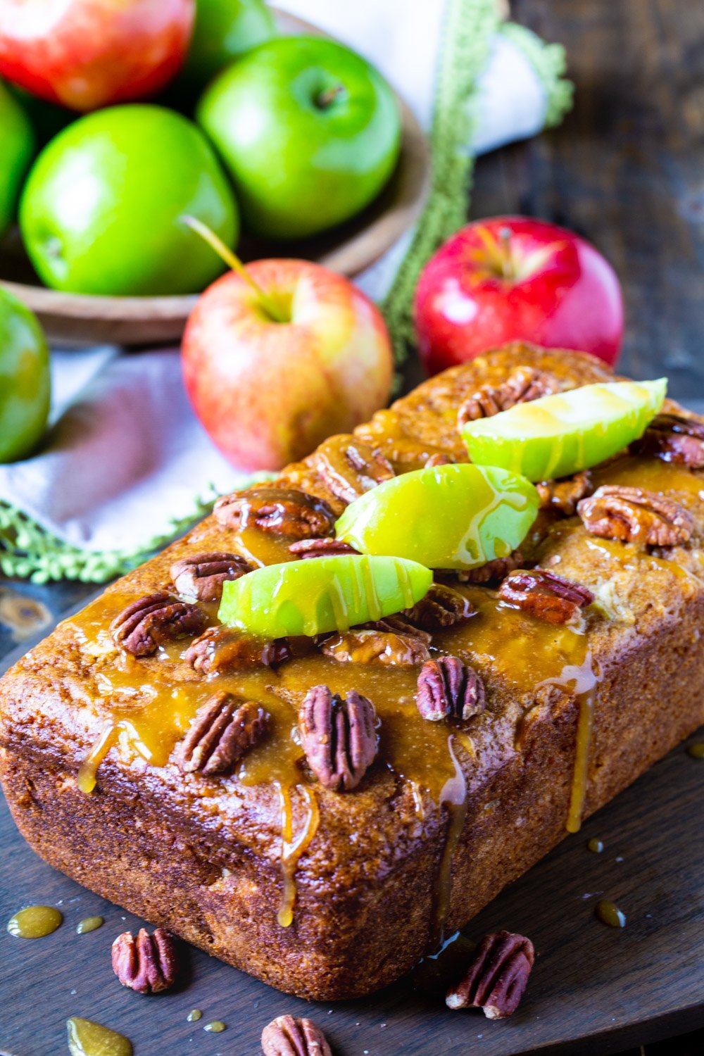Apple Bread loaf with bowl of apples behind it.