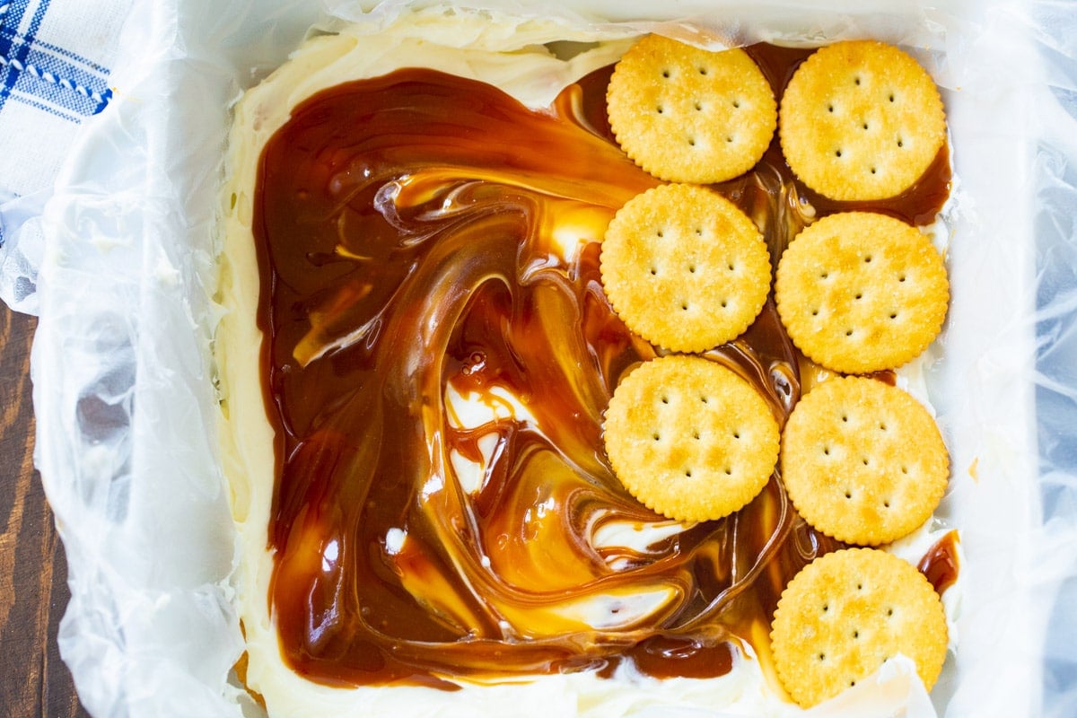 Crackers being layered on top of caramel sauce.