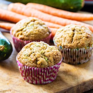 Three Carrot Zucchini Muffins on a wooden board.