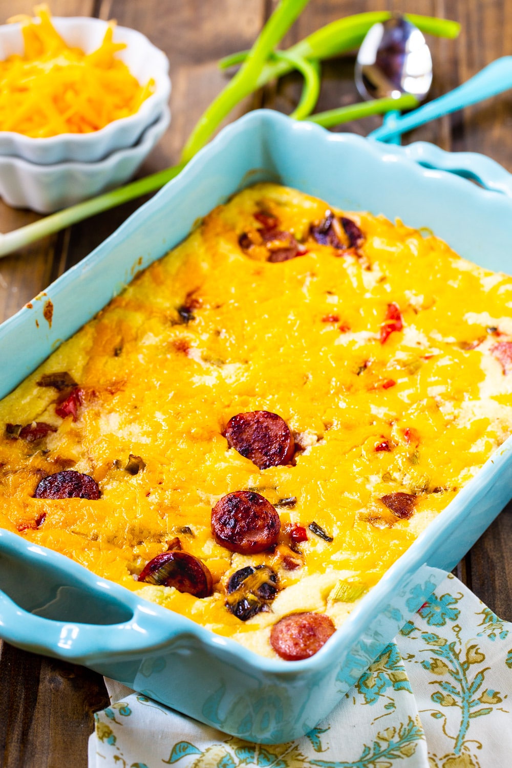 Cheesy Grits Casserole with Smoked Sausage in a blue casserole dish.