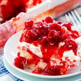 Slice of CHerry Poke Cake covered in cherries.