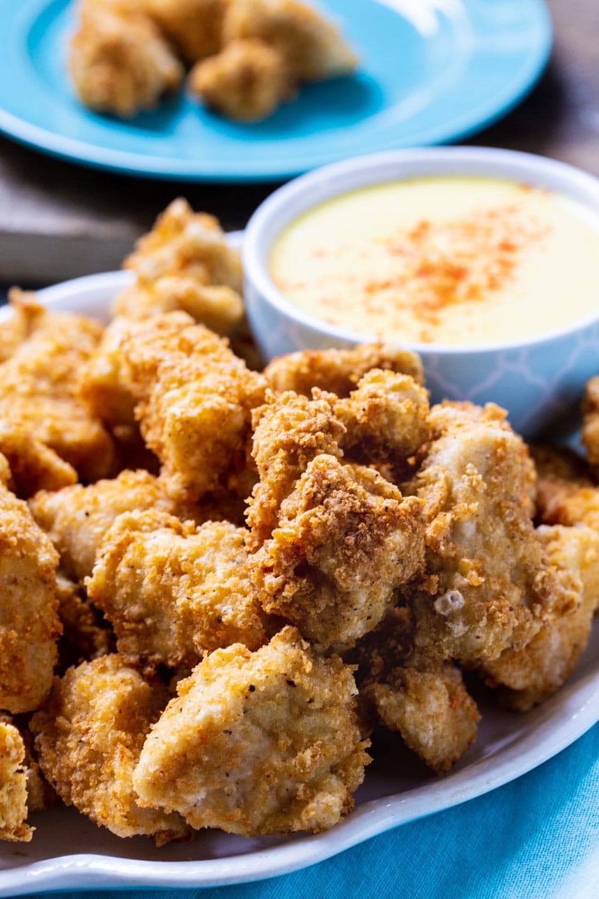 Chicken Nuggets piled up on plate with bowl of honey mustard.