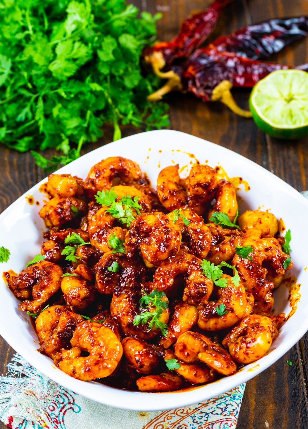 Shrimp in a bowl with a bunch of cilantro beside it.