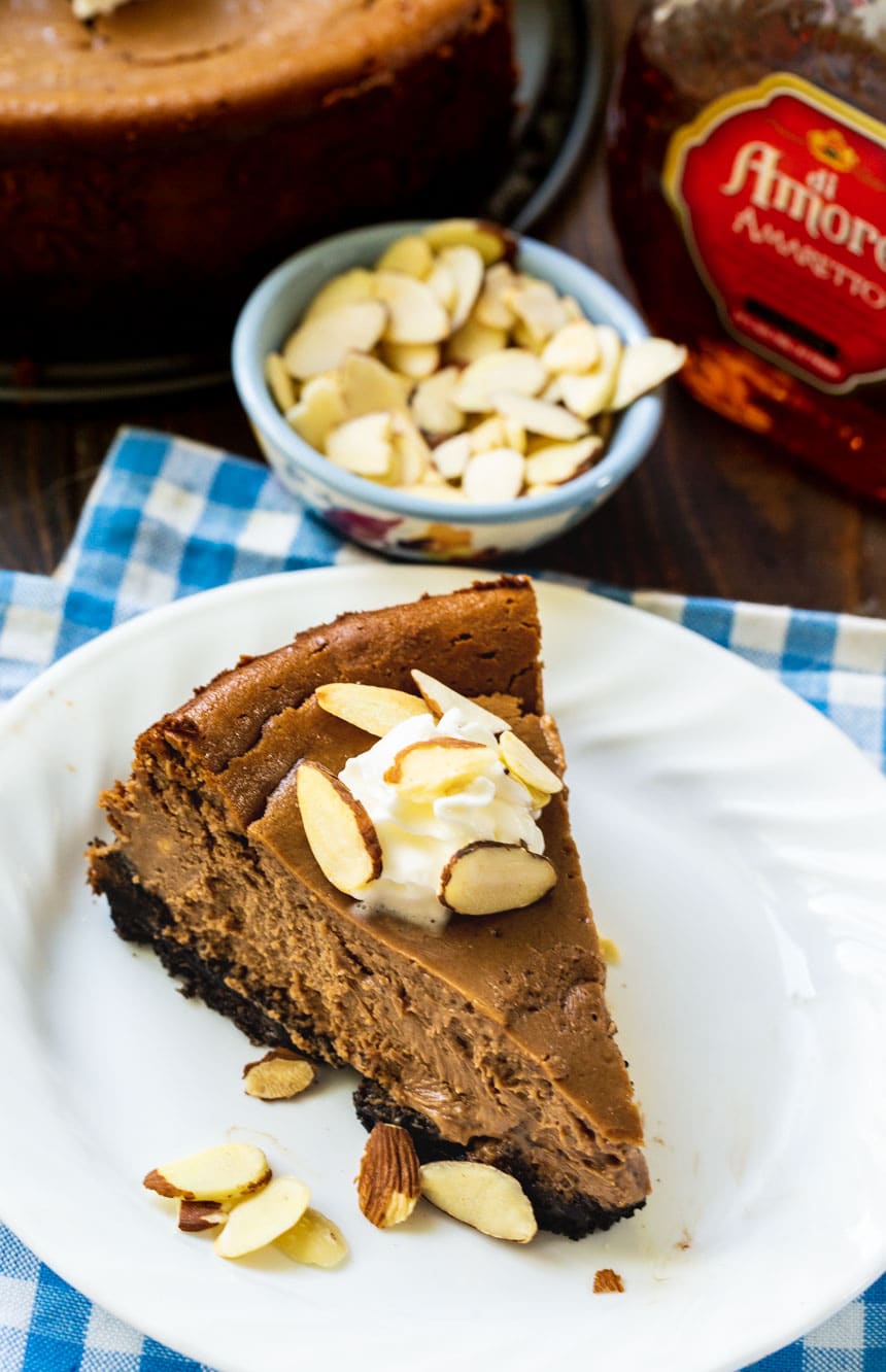 Slice of Chocolate Amaretto Cheesecake on plate with bowl of almonds.