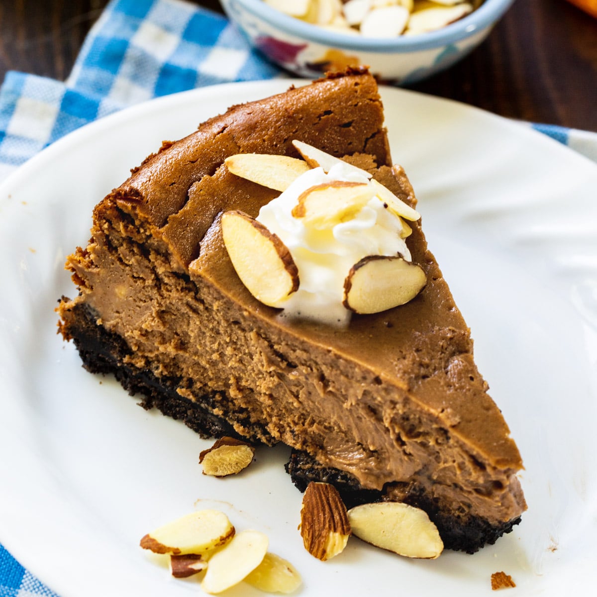 Slice of Chocolate Amaretto Cheesecake topped with whipped cream and sliced almonds.