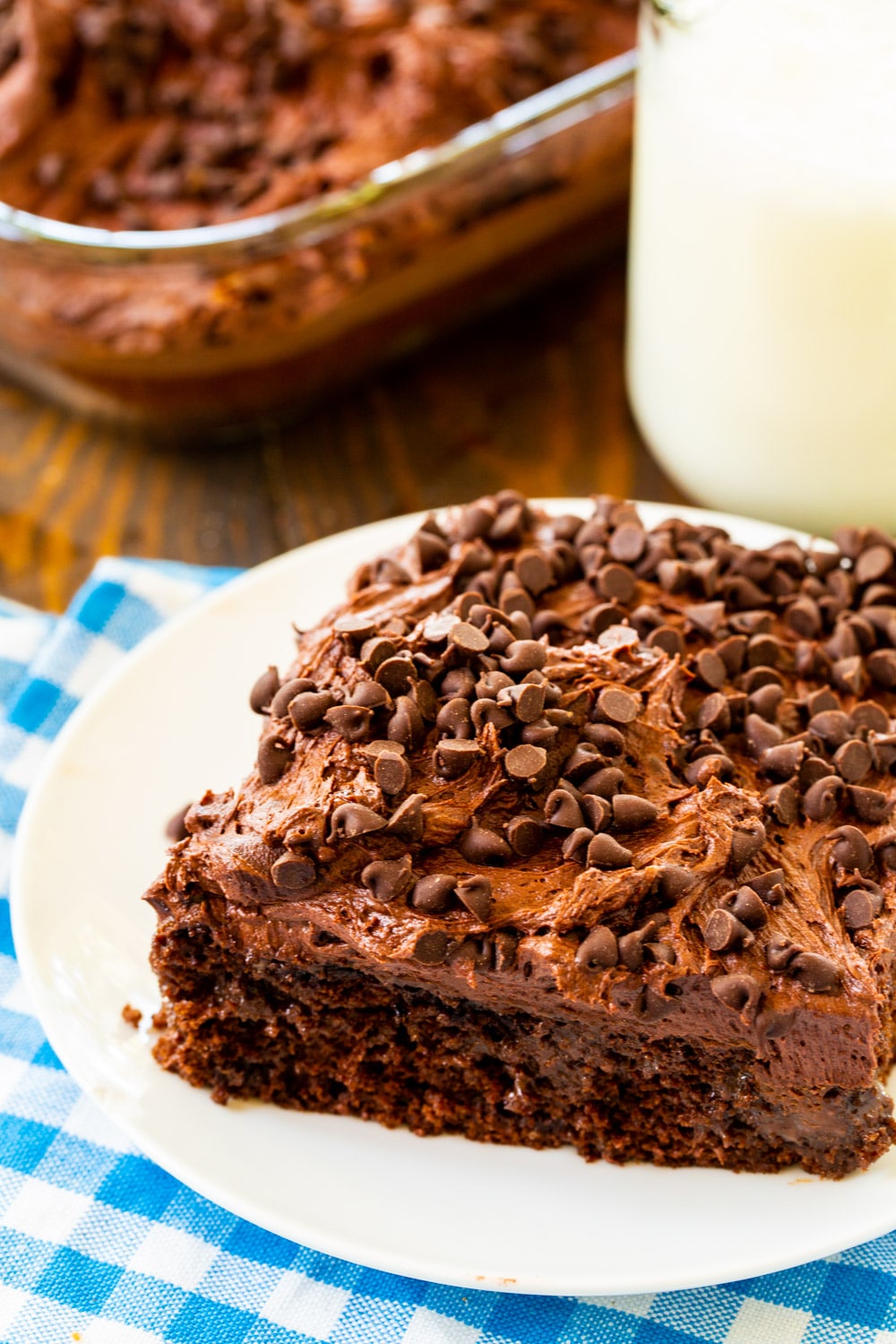 Chocolate Poke Cake on a plate with jug of milk.