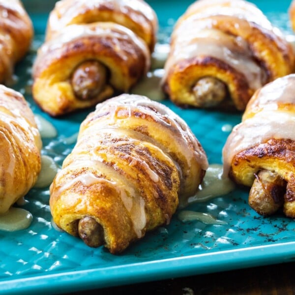 Cinnamon Roll Pigs in a Blanket on a blue baking sheet.