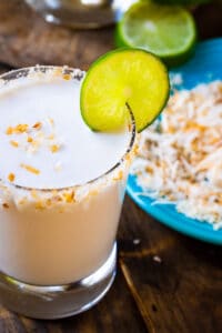 Coconut Margarita in a glass with toasted coconut around rim.