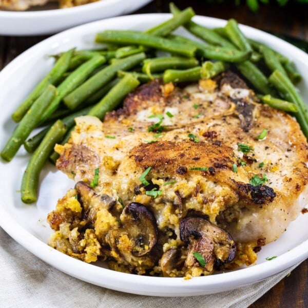 Cornbread Stuffed Pork Chops on a plate with green beans.