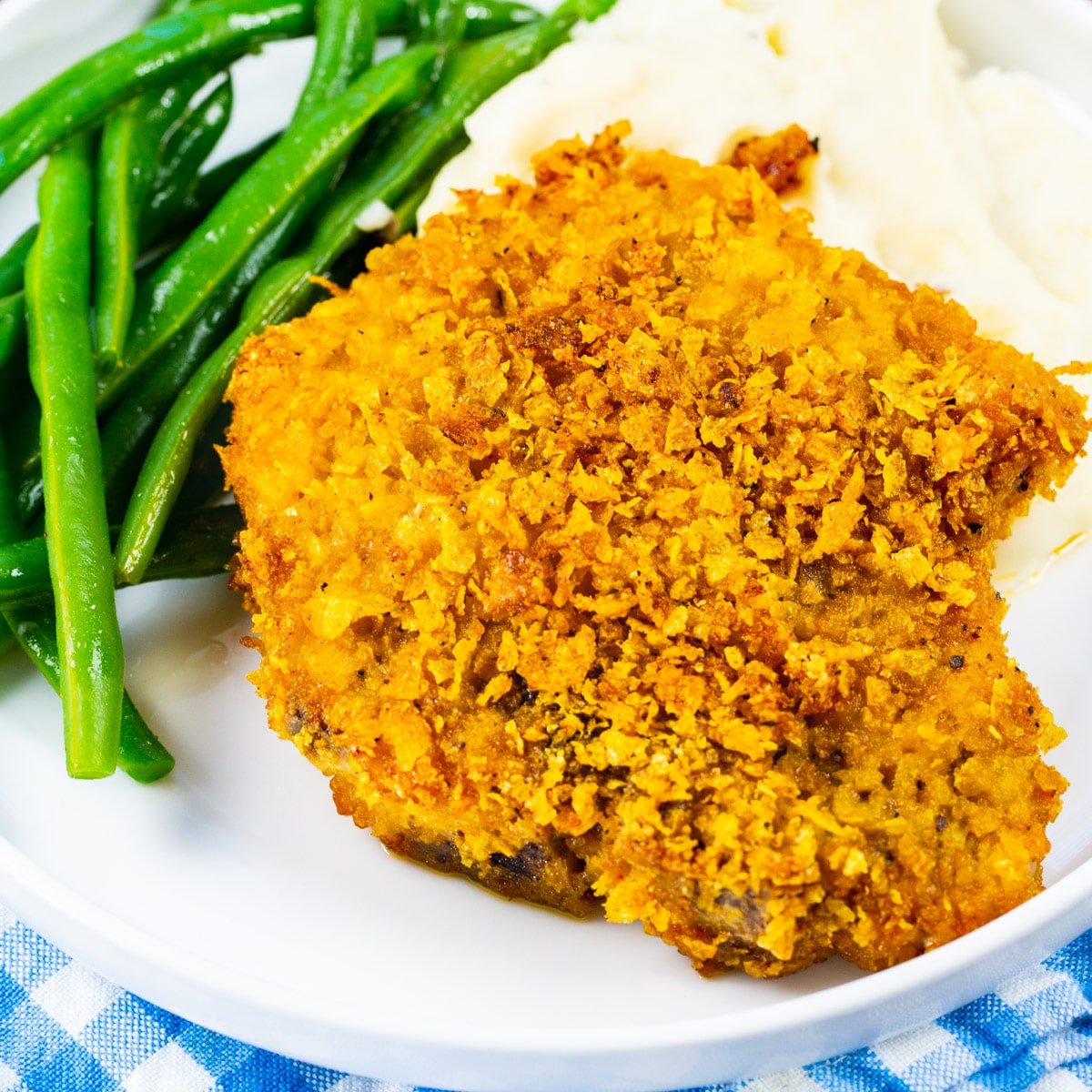 Cornflake Crusted Baked Pork Chops on plate with mashed potatoes and green beans.