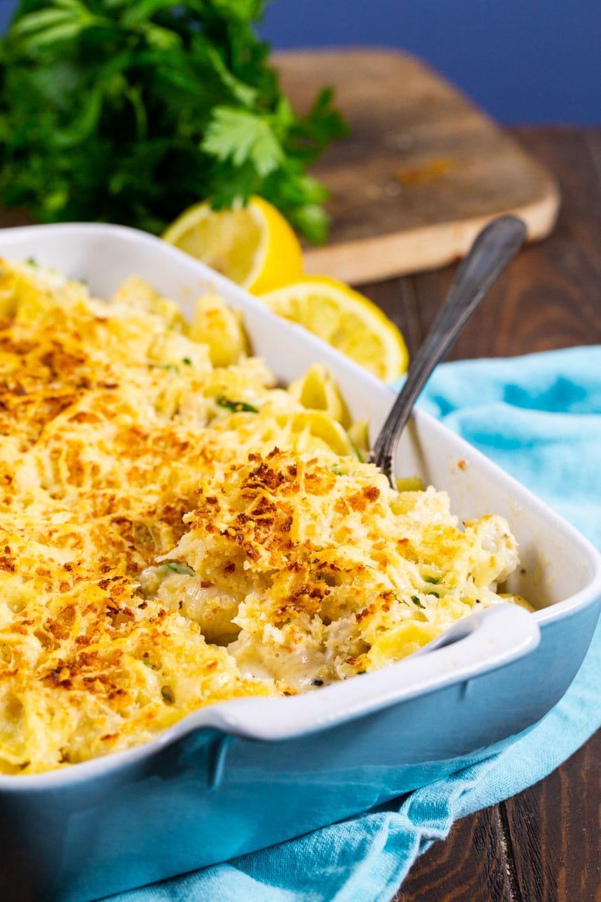 Spoon scooping Crab Alfredo Shells out of baking dish.