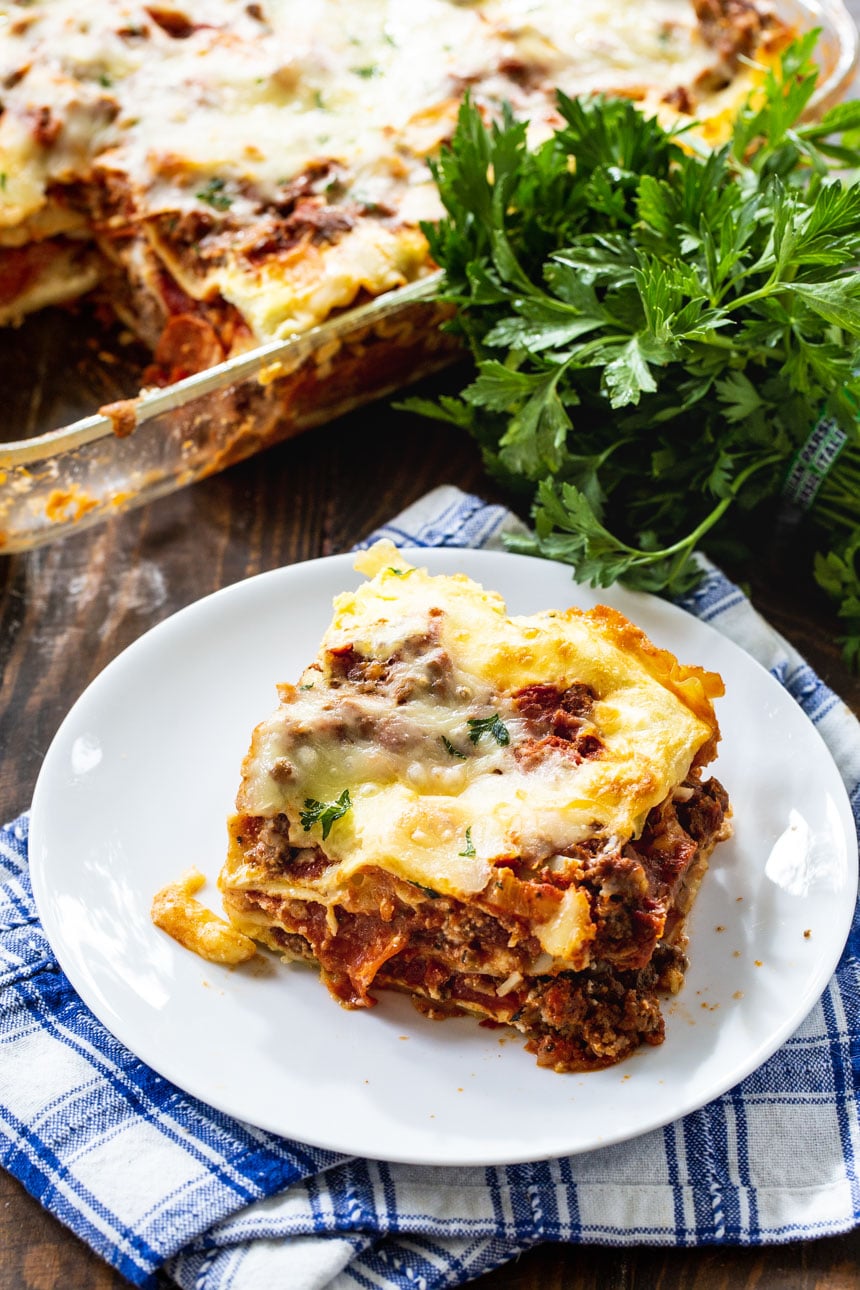 Slice of lasagna with parlsey behind it.