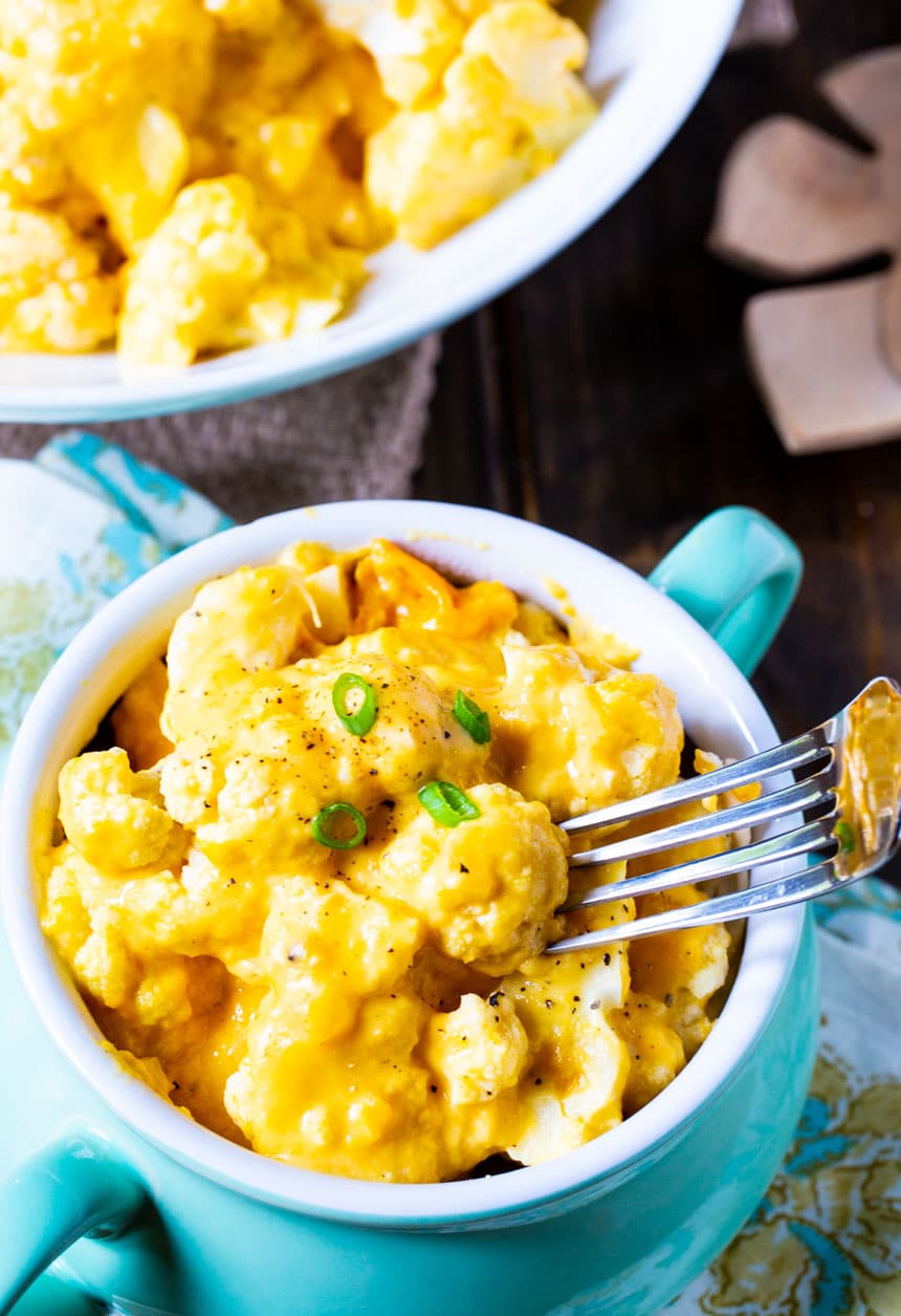 Fork lifting up piece of cauliflower and cheese.