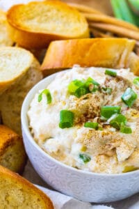 Crock Pot Crab Artichoke Dip in bowl surrounded by toasted baguette slices.