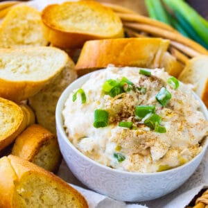 Crock Pot Crab Artichoke Dip in bowl surrounded by toasted baguette slices.