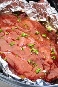 Crockpot Meatloaf lined with aluminum foil in slow cooker.