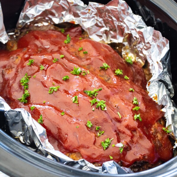 Crockpot Meatloaf lined with aluminum foil in slow cooker.