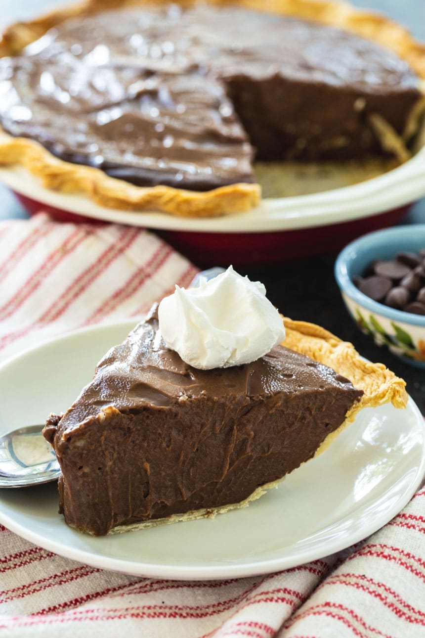 Slice of Dark Chocolate Pie on a plate with rest of pie in background.