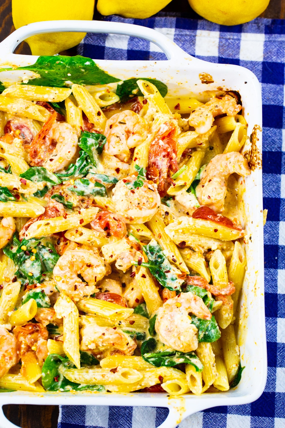 Penne with shrimp, feta and cherry tomatoes in white baking dish.